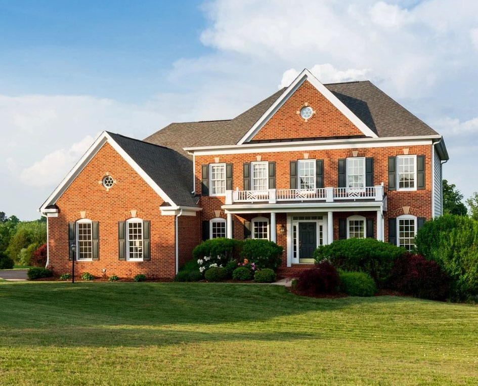 A large brick house with a lush green lawn.